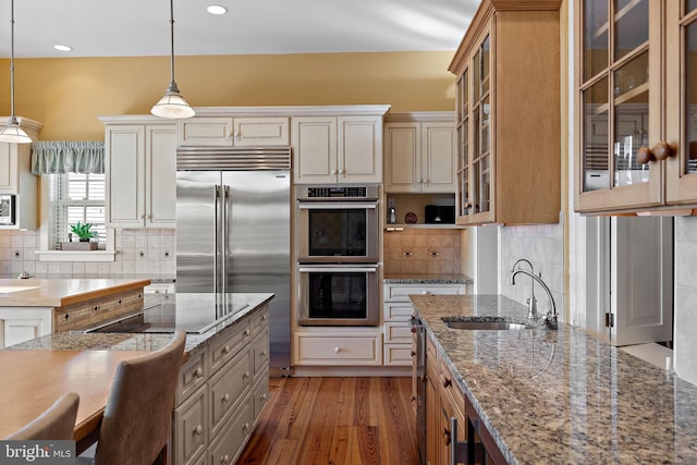 55 The Strand, New Castle, DE 19720 - kitchen featuring appliances with stainless steel finishes, a sink, light wood finished floors, decorative backsplash, and hanging light fixtures