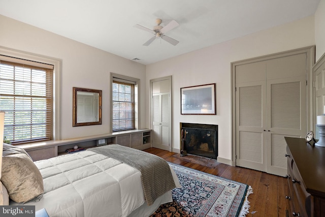 55 The Strand, New Castle, DE 19720 - bedroom featuring two closets, hardwood / wood-style flooring, a fireplace with flush hearth, ceiling fan, and baseboards