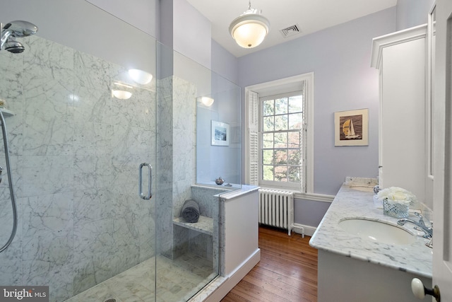 55 The Strand, New Castle, DE 19720 - full bathroom with radiator heating unit, a shower stall, wood-type flooring, double vanity, and baseboards