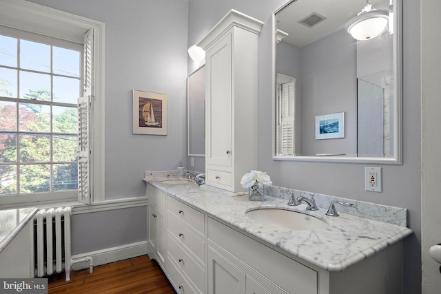 55 The Strand, New Castle, DE 19720 - full bathroom featuring radiator heating unit, double vanity, healthy amount of natural light, and wood finished floors