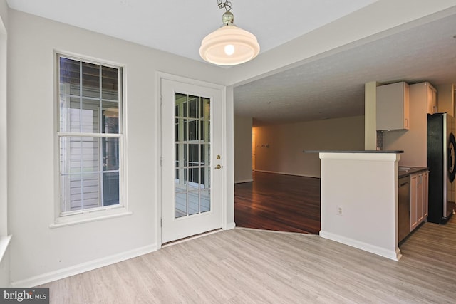 kitchen featuring appliances with stainless steel finishes, light wood-style floors, dark countertops, baseboards, and hanging light fixtures