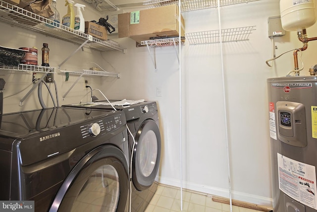 laundry room featuring water heater, baseboards, washer and dryer, and tile patterned floors