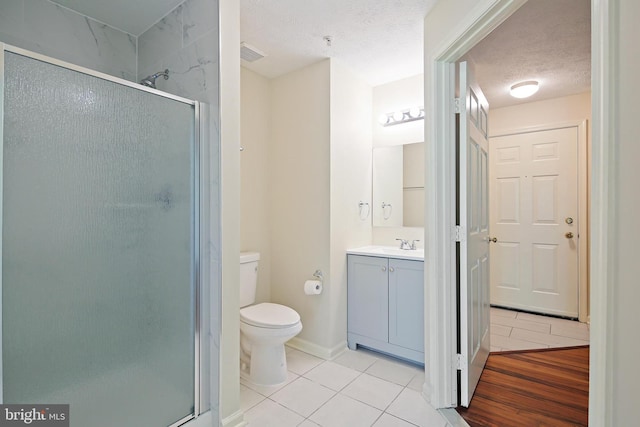 bathroom with tile patterned floors, a shower stall, vanity, toilet, and a textured ceiling