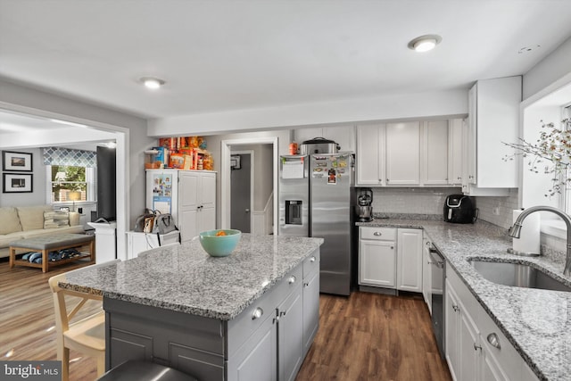 10317 Beaumont St, Fairfax, VA 22030 - kitchen with stainless steel appliances, a sink, dark wood-style flooring, tasteful backsplash, and light stone counters
