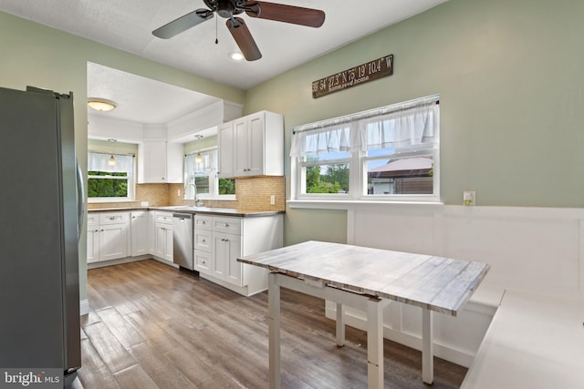 kitchen with stainless steel appliances, white cabinets, tasteful backsplash, and light wood-style flooring