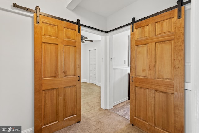 corridor featuring a barn door and light carpet