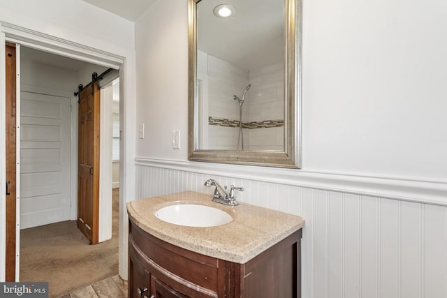 full bath with vanity, wainscoting, and a shower