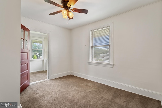 carpeted empty room with ceiling fan and baseboards