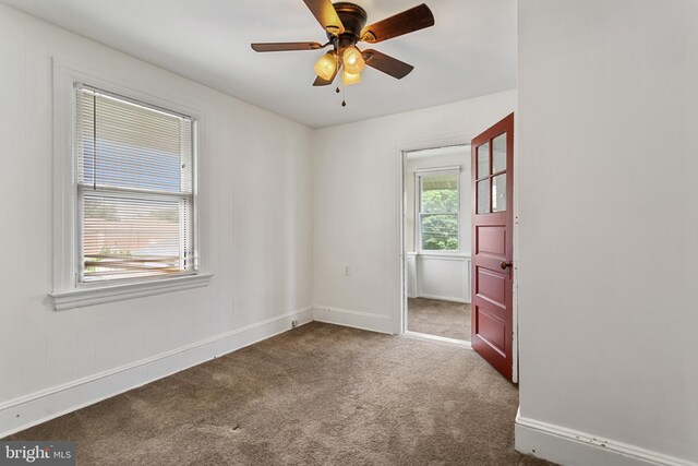 unfurnished room featuring dark colored carpet, baseboards, and a ceiling fan