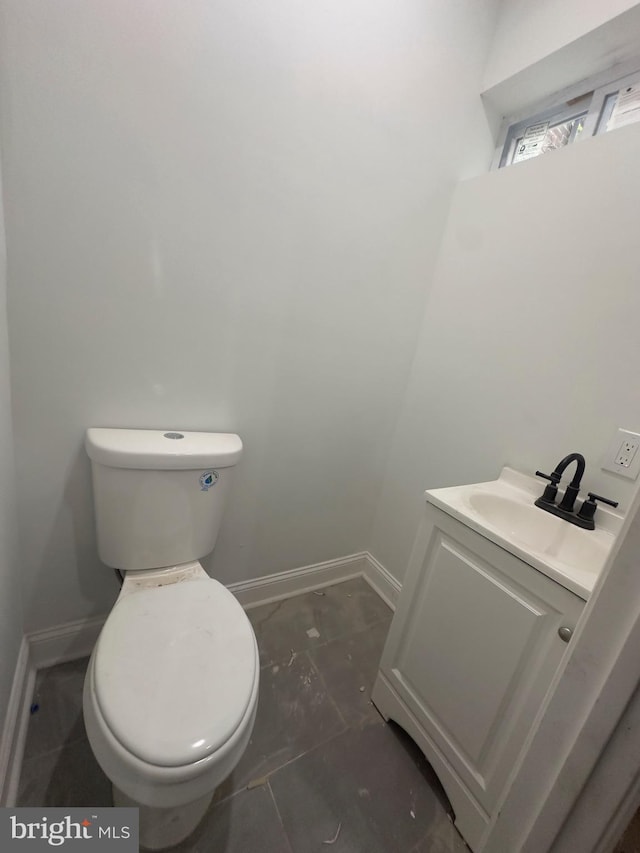 bathroom featuring baseboards, toilet, and vanity