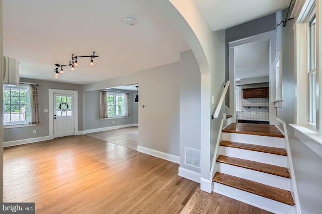 818 Glen Allen Dr, Baltimore, MD 21229 - stairway with arched walkways, baseboards, wood finished floors, and rail lighting