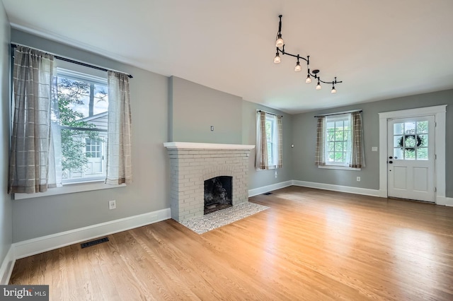 818 Glen Allen Dr, Baltimore, MD 21229 - unfurnished living room featuring baseboards, wood finished floors, rail lighting, and a brick fireplace