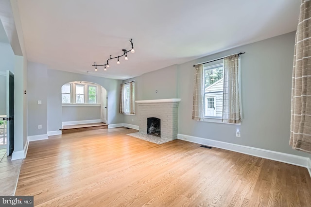 818 Glen Allen Dr, Baltimore, MD 21229 - unfurnished living room featuring arched walkways, wood finished floors, a fireplace, rail lighting, and baseboards