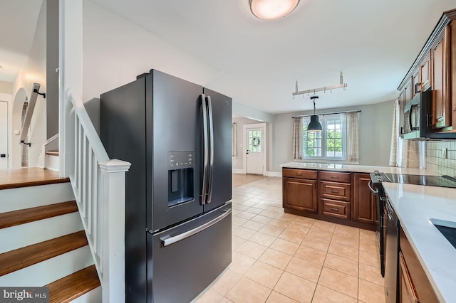 818 Glen Allen Dr, Baltimore, MD 21229 - kitchen with black fridge with ice dispenser, stainless steel microwave, light tile patterned floors, and light countertops