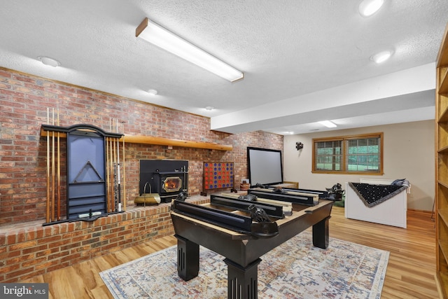 3 Franklin St, Stafford, VA 22556 - playroom featuring a wood stove, a textured ceiling, brick wall, and wood finished floors