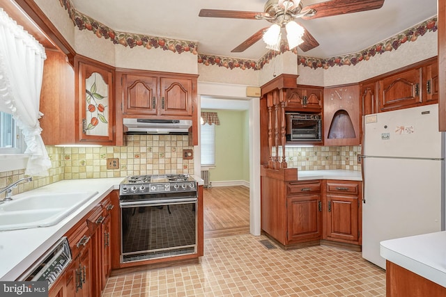 27 N Warren St, Woodbury, NJ 08096 - kitchen with freestanding refrigerator, gas range oven, under cabinet range hood, a sink, and light countertops