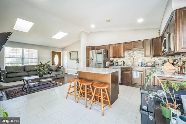 9185 Winterset Dr, Manassas, VA 20110 - kitchen with stainless steel appliances, a breakfast bar, open floor plan, a skylight, and a center island