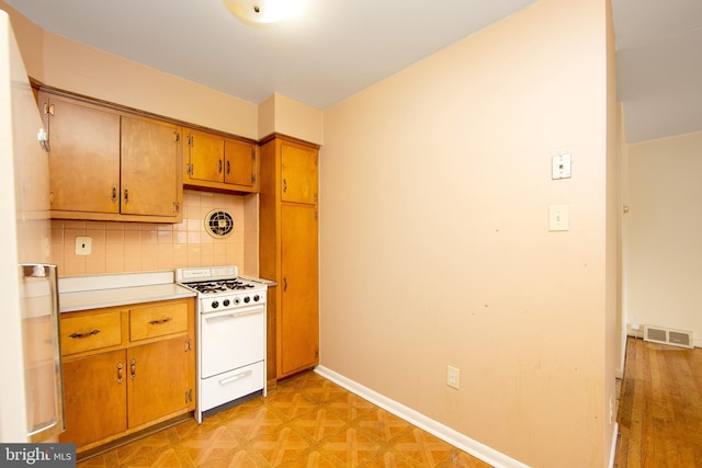 4021 Balwynne Park Rd, Philadelphia, PA 19131 - kitchen with white gas range, brown cabinets, light countertops, tasteful backsplash, and baseboards