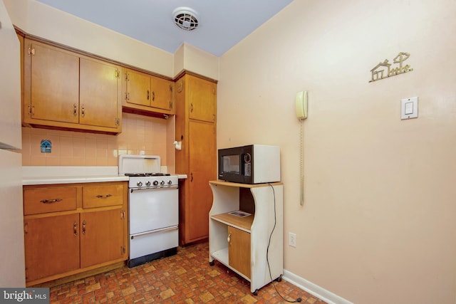 4021 Balwynne Park Rd, Philadelphia, PA 19131 - kitchen with white range with gas stovetop, black microwave, light countertops, tasteful backsplash, and brown cabinets