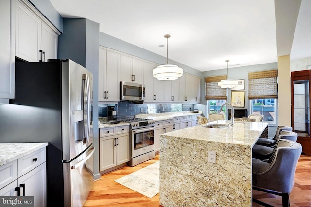 440 Belmont Bay Dr Unit 406, Woodbridge, VA 22191 - kitchen with appliances with stainless steel finishes, a sink, backsplash, light wood finished floors, and a breakfast bar area