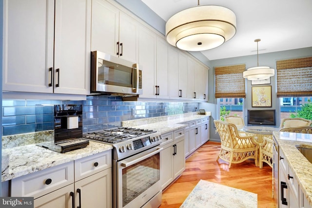 440 Belmont Bay Dr Unit 406, Woodbridge, VA 22191 - kitchen with appliances with stainless steel finishes, light wood-style flooring, backsplash, light stone counters, and pendant lighting