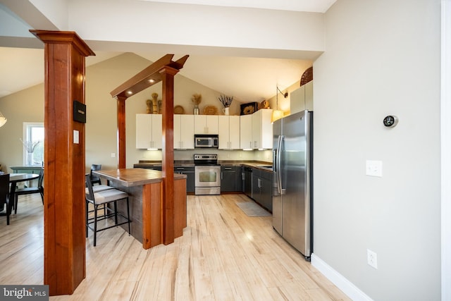 311 Summit Woods Dr, Mc Henry, MD 21541 - kitchen with stainless steel appliances, dark countertops, light wood-style floors, a breakfast bar, and high vaulted ceiling