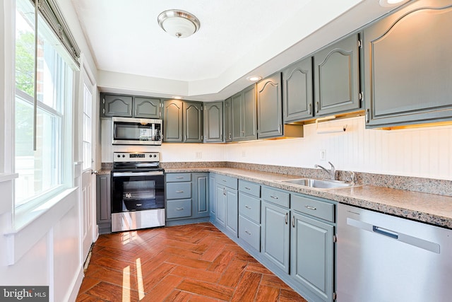kitchen featuring stainless steel appliances, a sink, and light countertops