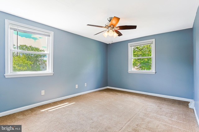 carpeted empty room featuring baseboards and a ceiling fan