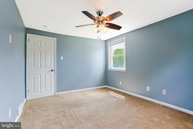 carpeted spare room featuring ceiling fan and baseboards