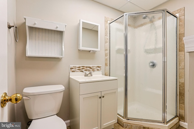 bathroom with backsplash, a shower stall, toilet, and vanity