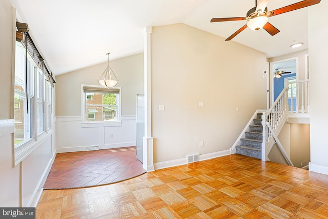 unfurnished room with ceiling fan, lofted ceiling, stairway, and a wainscoted wall