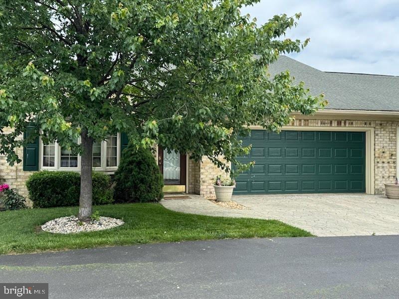 12953 Little Hayden Cir, Hagerstown, MD 21742 - obstructed view of property with concrete driveway, an attached garage, a shingled roof, brick siding, and a front lawn