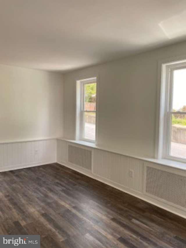 70 Chestnut St, Mohnton, PA 19540 - spare room featuring wainscoting, healthy amount of natural light, dark wood-style floors, a decorative wall, and radiator heating unit
