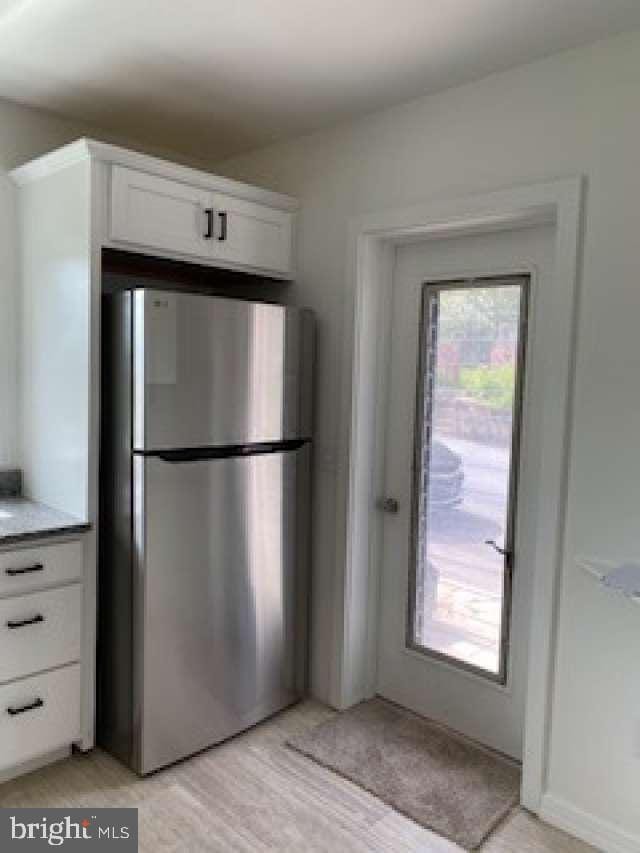 70 Chestnut St, Mohnton, PA 19540 - kitchen with freestanding refrigerator, white cabinets, light countertops, and light wood-style floors