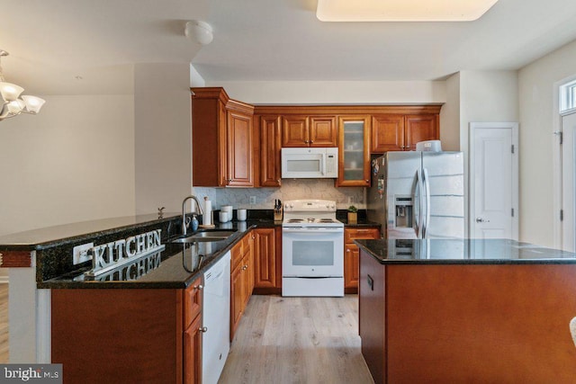 kitchen with white appliances, a sink, light wood-type flooring, and brown cabinetry