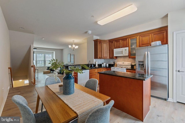 kitchen featuring white appliances, a chandelier, a kitchen island, brown cabinetry, and light wood-style floors