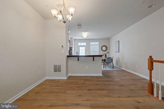 empty room featuring wood finished floors, a chandelier, and baseboards
