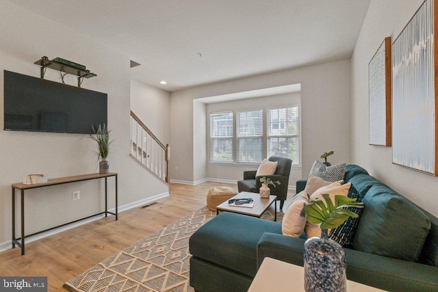 living room featuring stairs, wood finished floors, baseboards, and recessed lighting
