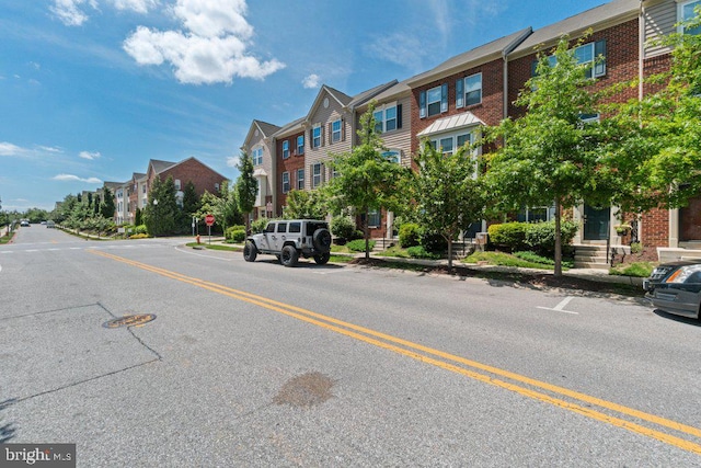 view of asphalt street featuring a residential view, curbs, traffic signs, and sidewalks