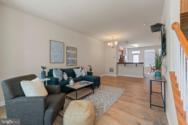 living room with stairs, a chandelier, wood finished floors, and baseboards