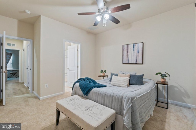 bedroom featuring light carpet, baseboards, ensuite bath, and a ceiling fan