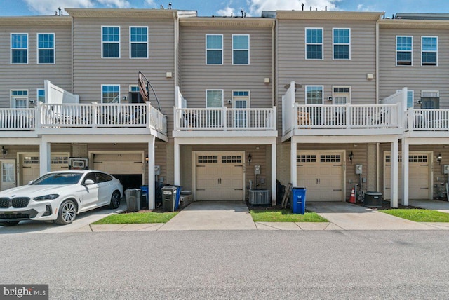 rear view of property with an attached garage, driveway, and central AC