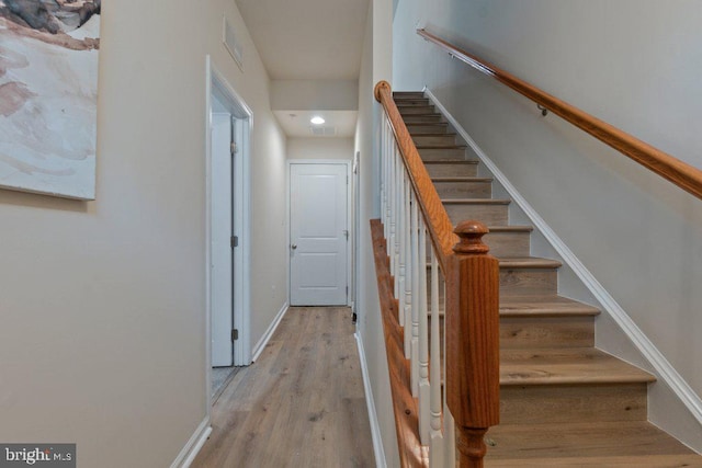 stairs featuring wood finished floors, baseboards, and recessed lighting