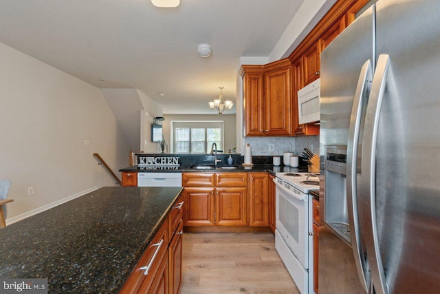 kitchen with white appliances, a sink, a chandelier, and brown cabinets