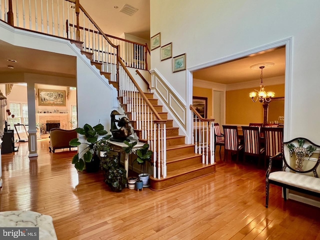 4718 Village Dr, Fairfax, VA 22030 - staircase with a towering ceiling, hardwood / wood-style flooring, a chandelier, a fireplace, and crown molding