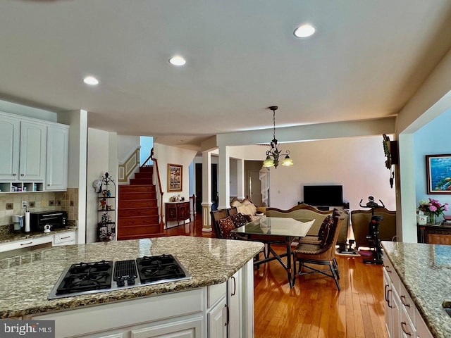 4718 Village Dr, Fairfax, VA 22030 - kitchen featuring stainless steel gas stovetop, white cabinets, light stone countertops, open floor plan, and recessed lighting