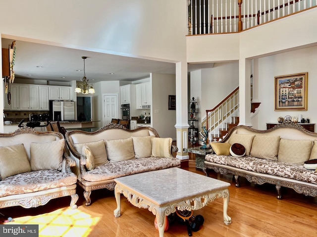 4718 Village Dr, Fairfax, VA 22030 - living area featuring a chandelier, light wood-style flooring, a towering ceiling, and decorative columns