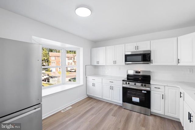 1065 Old Forge Rd, New Castle, DE 19720 - kitchen featuring stainless steel appliances, decorative backsplash, light wood-style floors, and white cabinetry