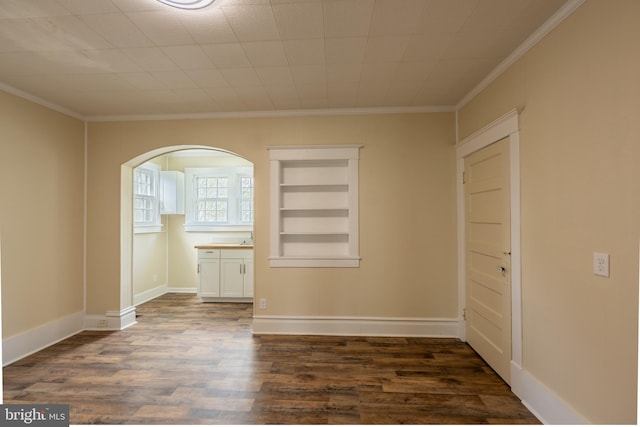 89 Main St N, Kilmarnock, VA 22482 - spare room with dark wood finished floors, ornamental molding, arched walkways, baseboards, and built in shelves
