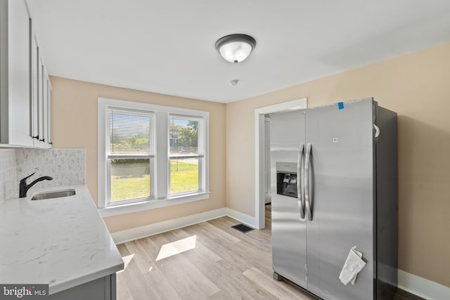 311 W Washington St, Paulsboro, NJ 08066 - kitchen with stainless steel refrigerator with ice dispenser, a sink, baseboards, backsplash, and light wood-style floors